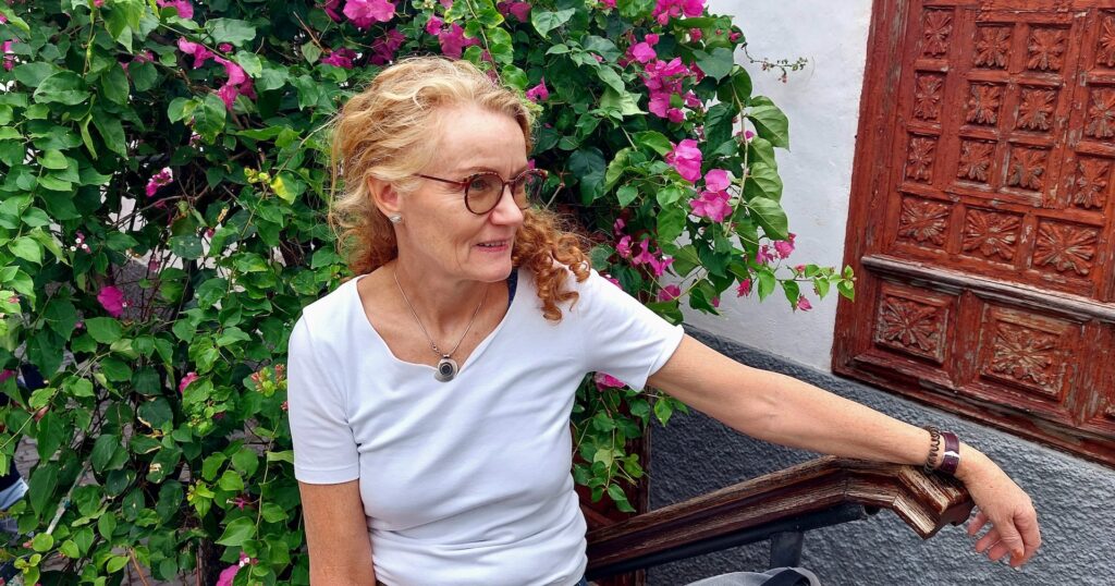 Barbara Kast vor einem Tor mit Bougenvillen